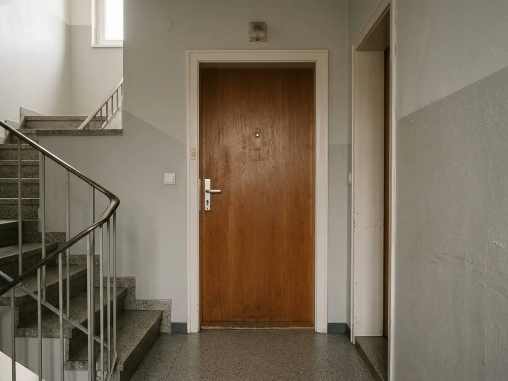 Geschlossene braune Wohnungstür im Stiegenhaus vor der Öffnung